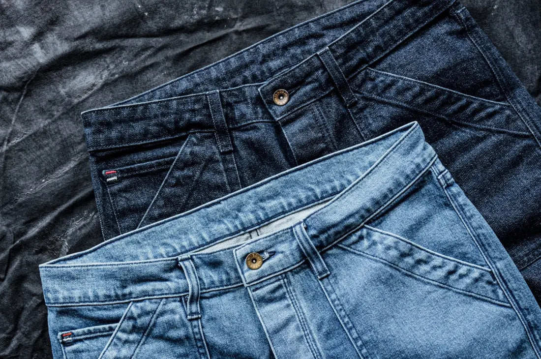 Best American denim jeans in dark and light blue washes laid flat on a dark background.