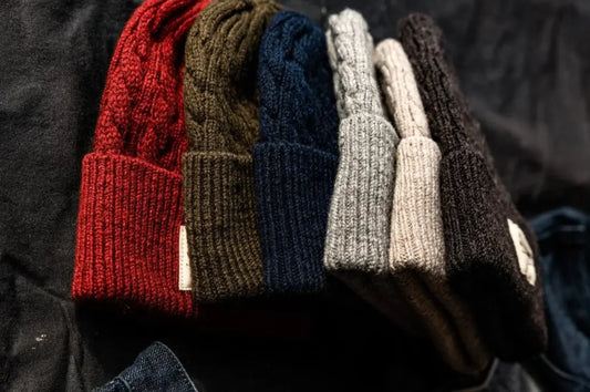 Knitted wool beanies stacked in multiple colors, emphasizing warmth, durability, and classic winter style