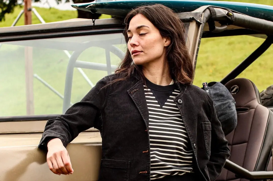 Durable denim clothing worn by woman leaning on off-road vehicle in casual outdoor setting.