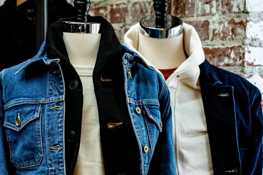 Ethical denim jeans jackets displayed on mannequins with contrasting inner layers against a brick wall backdrop.