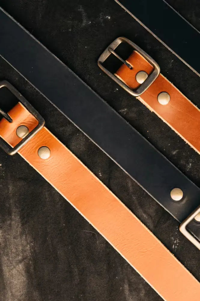 Latigo Belt 1.5-inch made from 8oz American Latigo Leather in black & brown, laid on a dark fabric background