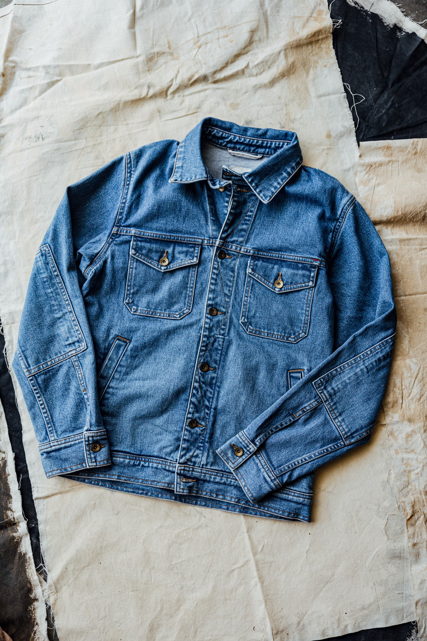 American made denim jacket displayed on a rustic fabric background.