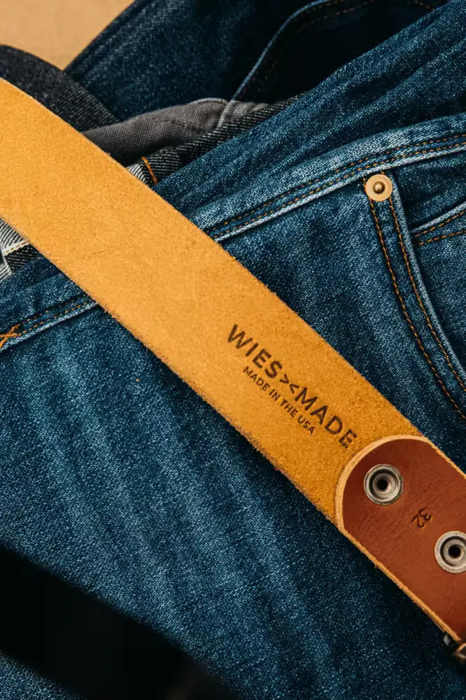 Wiesz-Made Latigo leather belt resting on blue denim jeans with visible stitching and brass hardware