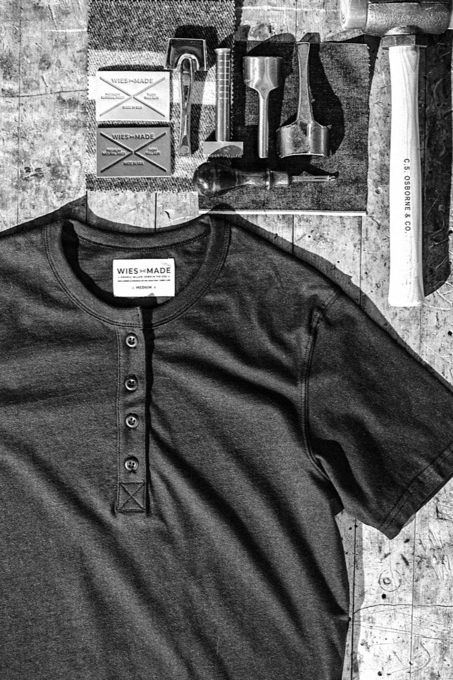 Four-button Reyes Henley shirt laid flat on a workbench with leather tools and WiesMade labels.
