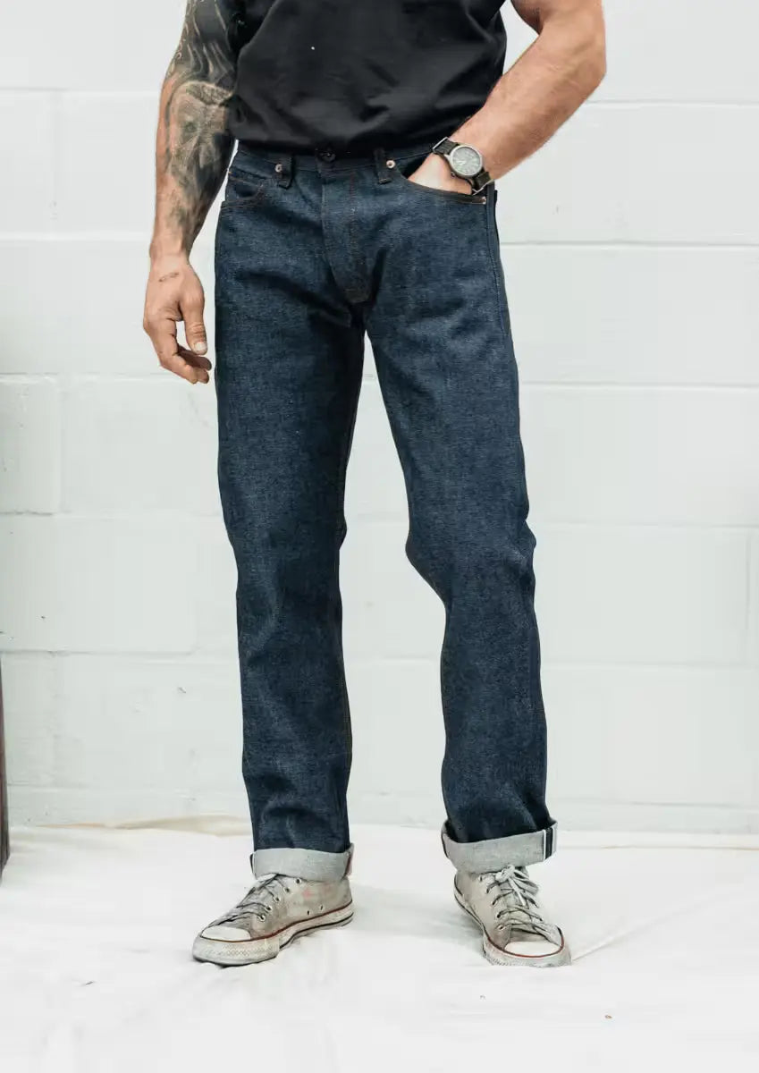 Man wearing Jack Fit jeans in Raw Selvedge Denim color featuring a straight-leg cut and rolled cuffs showcasing the selvedge edge