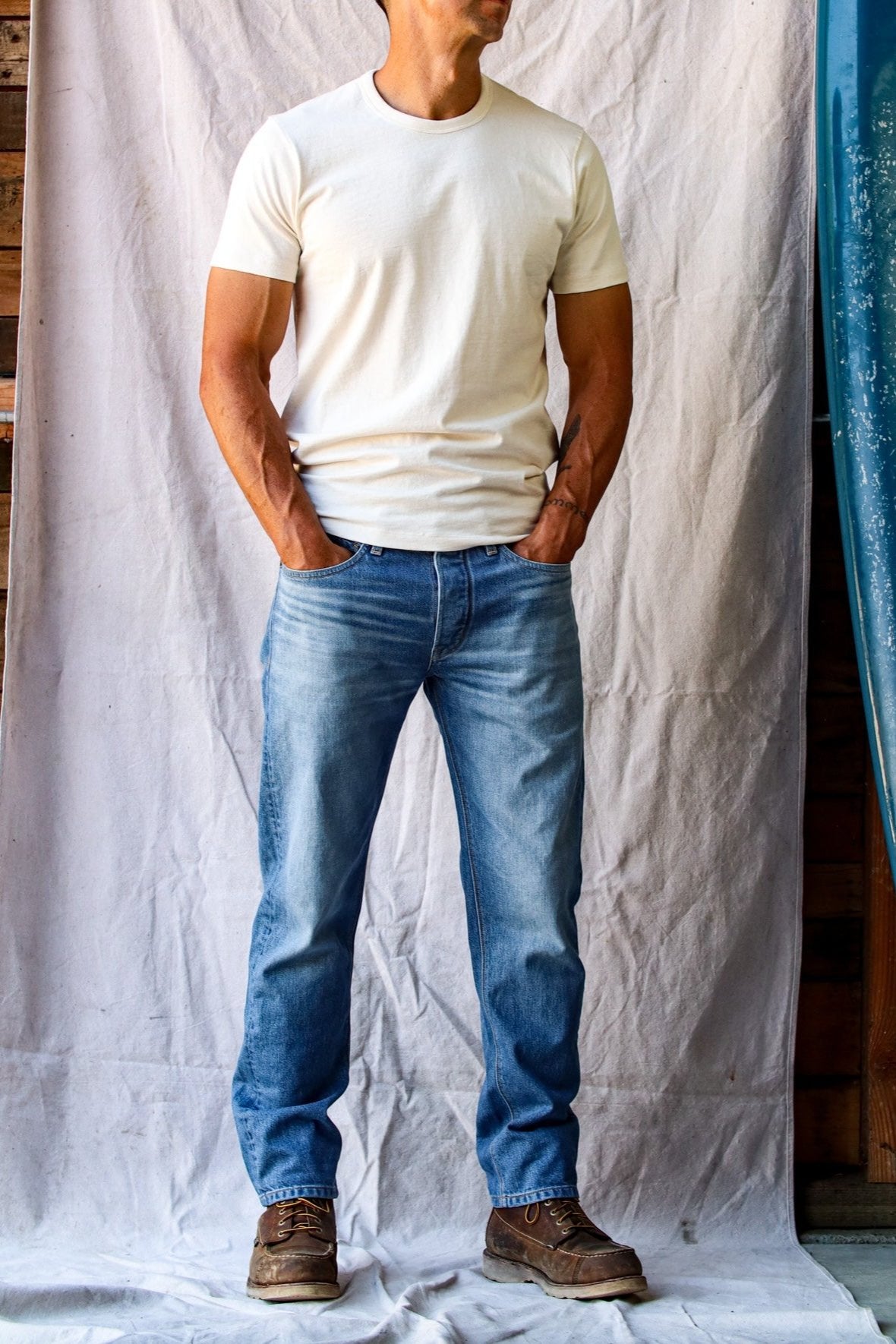 American denim jeans in a light wash with natural fading, paired with a white t-shirt and brown leather boots.