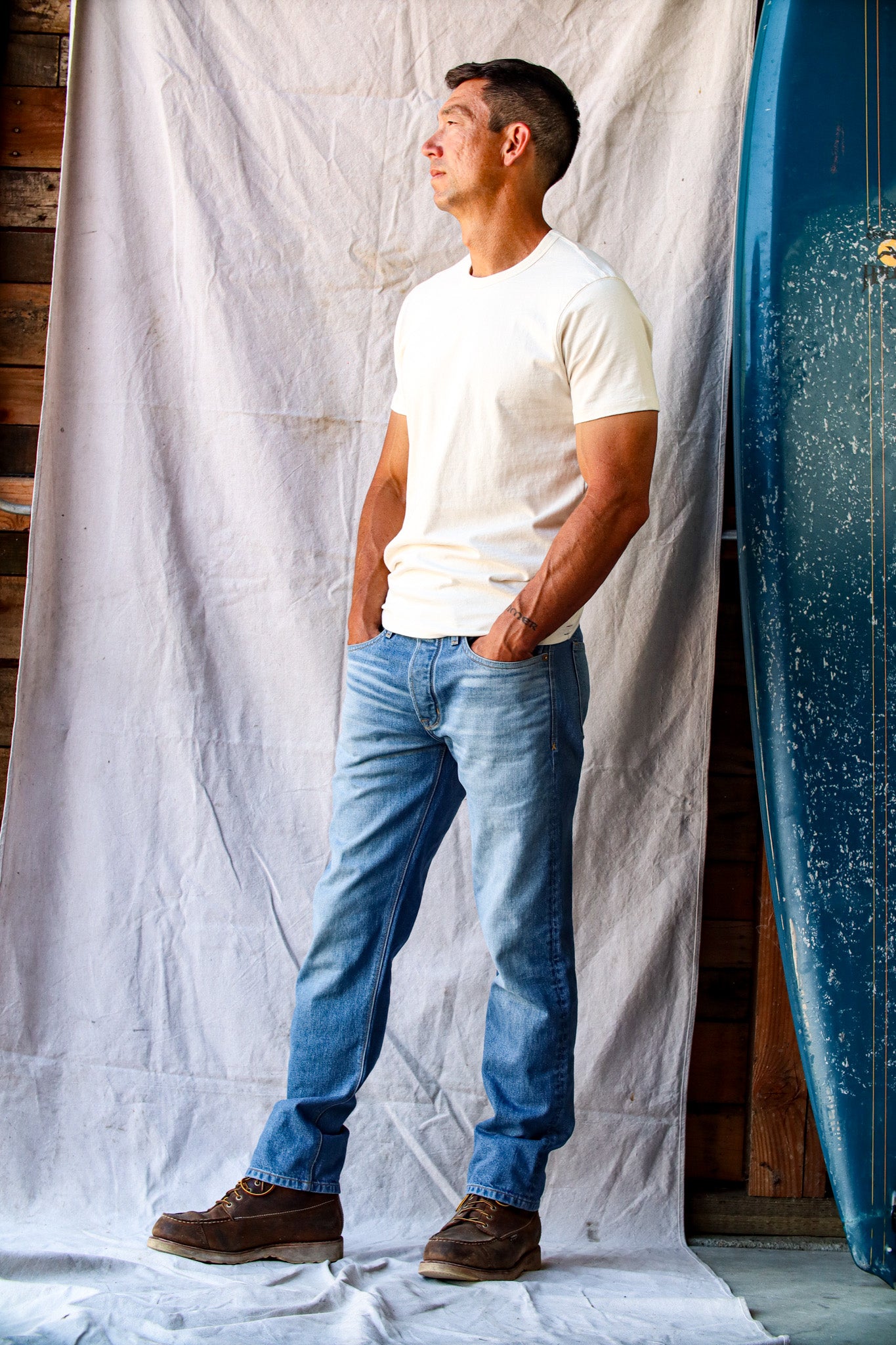 Real denim jeans in a light wash, worn by a man with a white t-shirt and brown work boots.