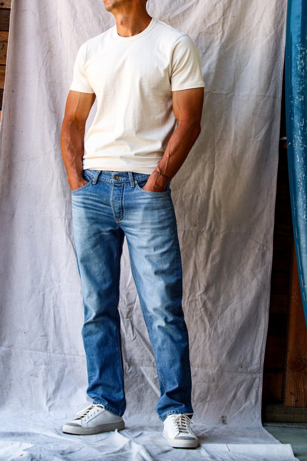 American denim jeans in a light wash, worn by a man with a white t-shirt and white sneakers.