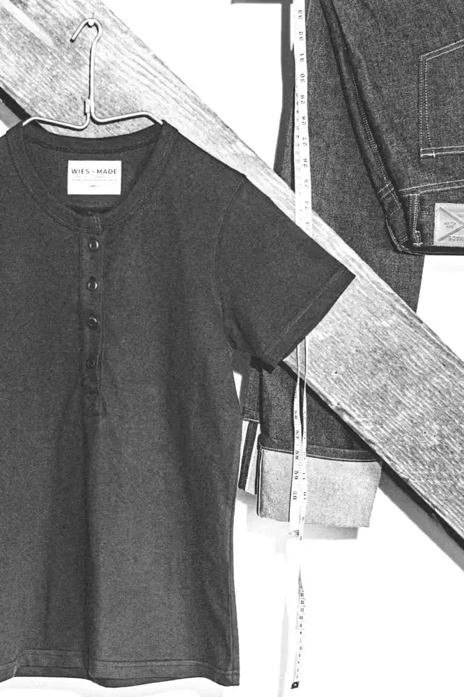 Reyes Henley shirt in black and white theme, heavyweight 8oz 100% cotton fabric, hanging on a metal hanger with jeans in the background