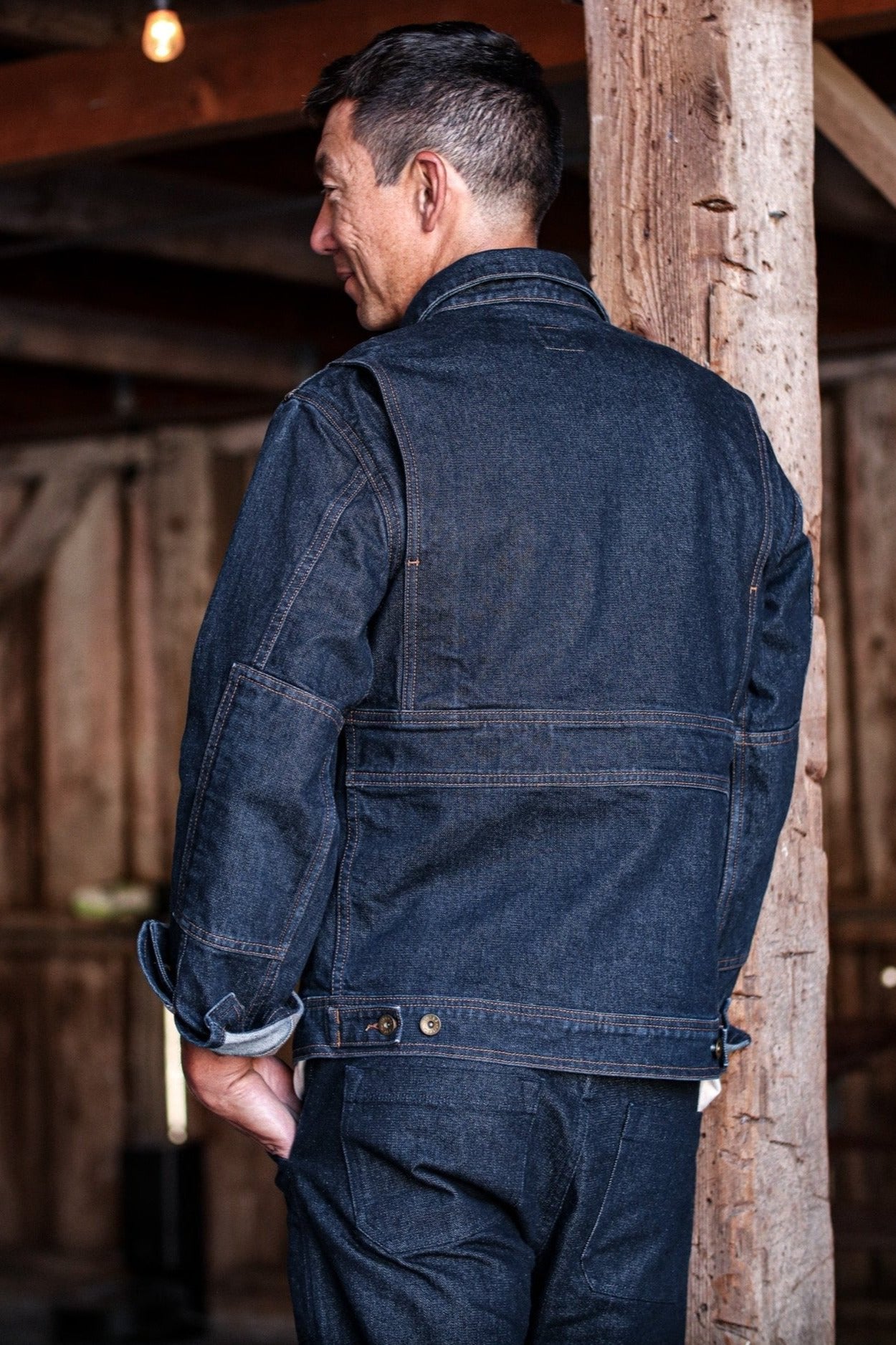 Denim jacket made in USA with a back view showcasing durable stitching and side adjustment buttons.