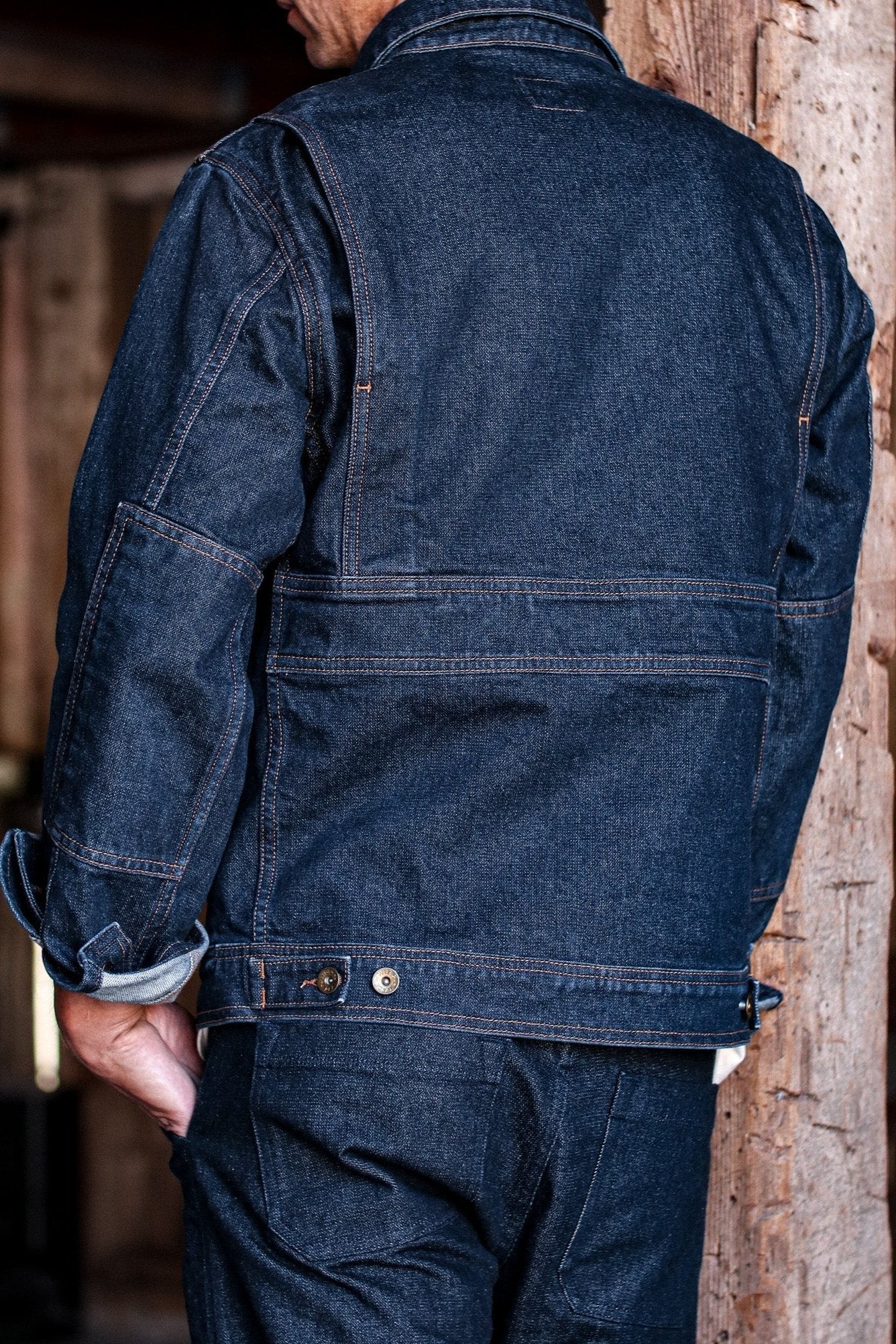 American made denim jacket with a back view highlighting reinforced seams and adjustable buttoned waist tabs.