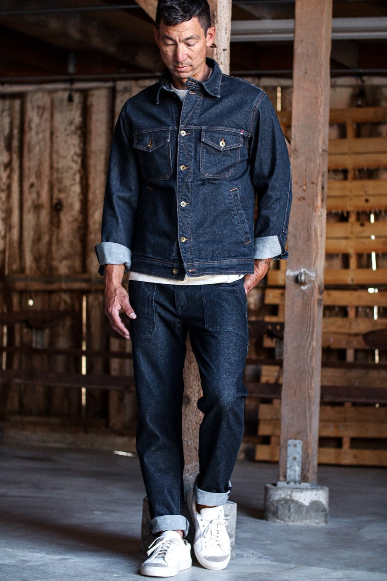 Denim jacket made in USA paired with dark jeans and white sneakers, styled for a casual yet rugged look.