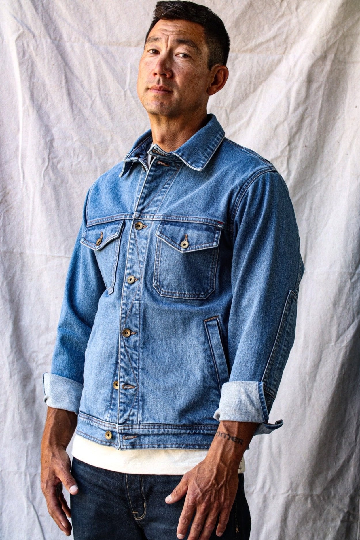 Made in USA denim jacket worn by a man standing against a neutral fabric backdrop.