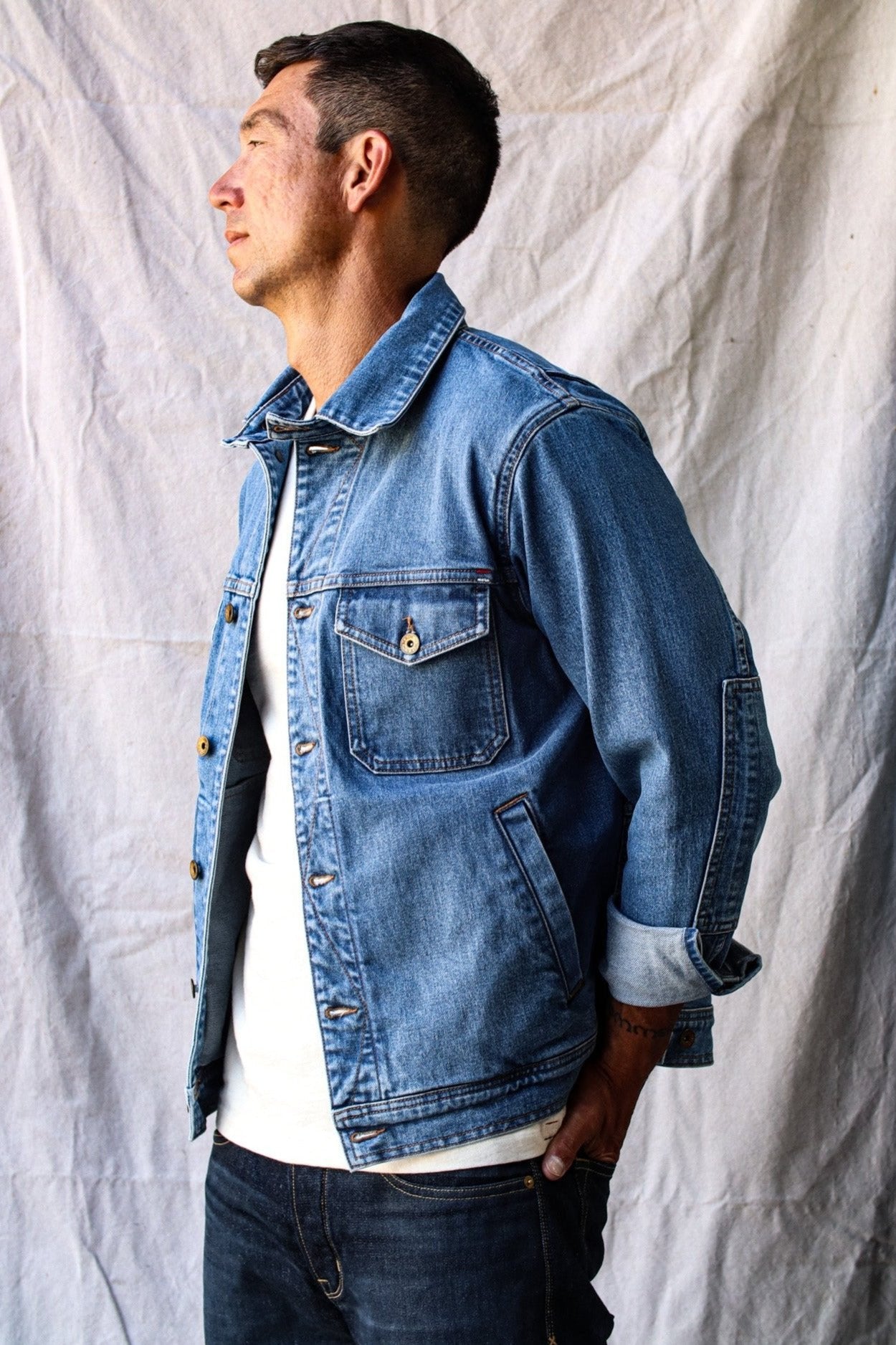 American made jacket featuring classic denim styling, worn by a man against a neutral fabric backdrop.