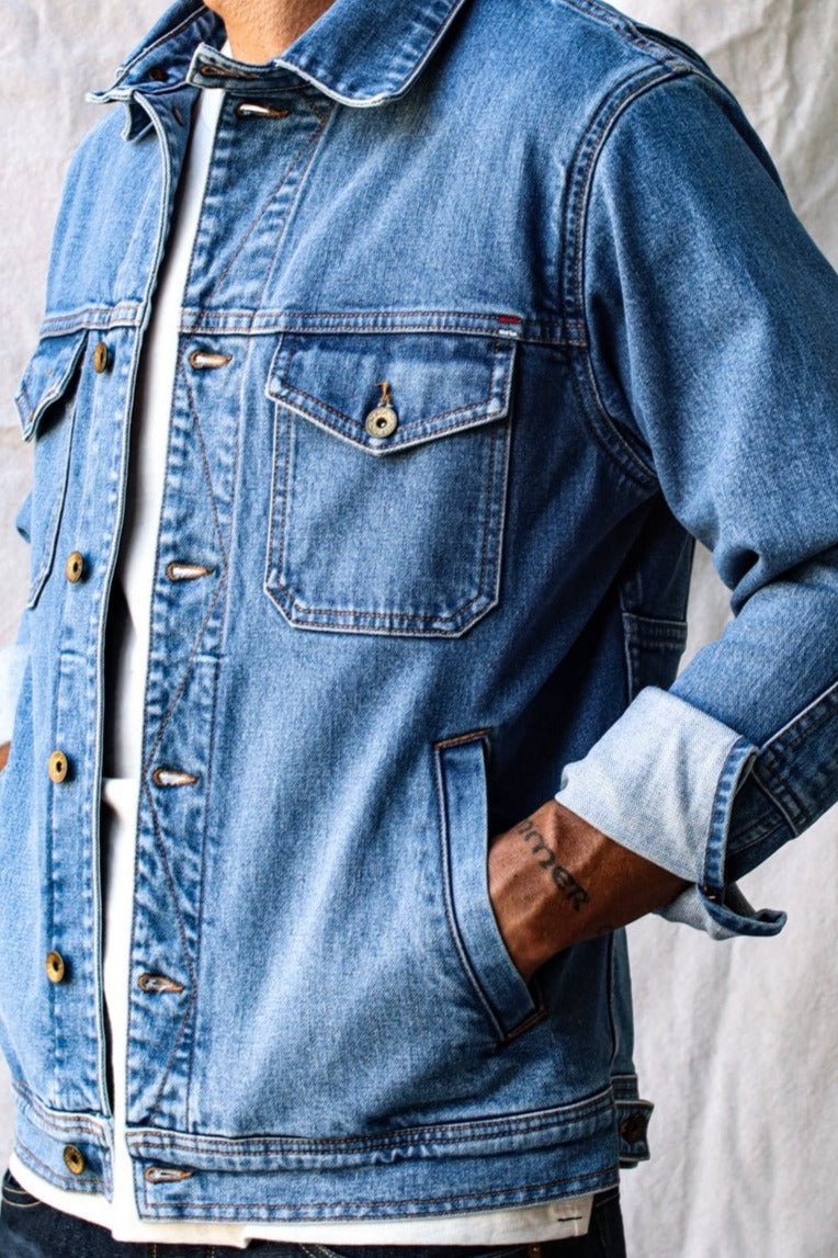 Heavy canvas jacket styled in classic blue denim with rolled cuffs, paired with a white shirt.