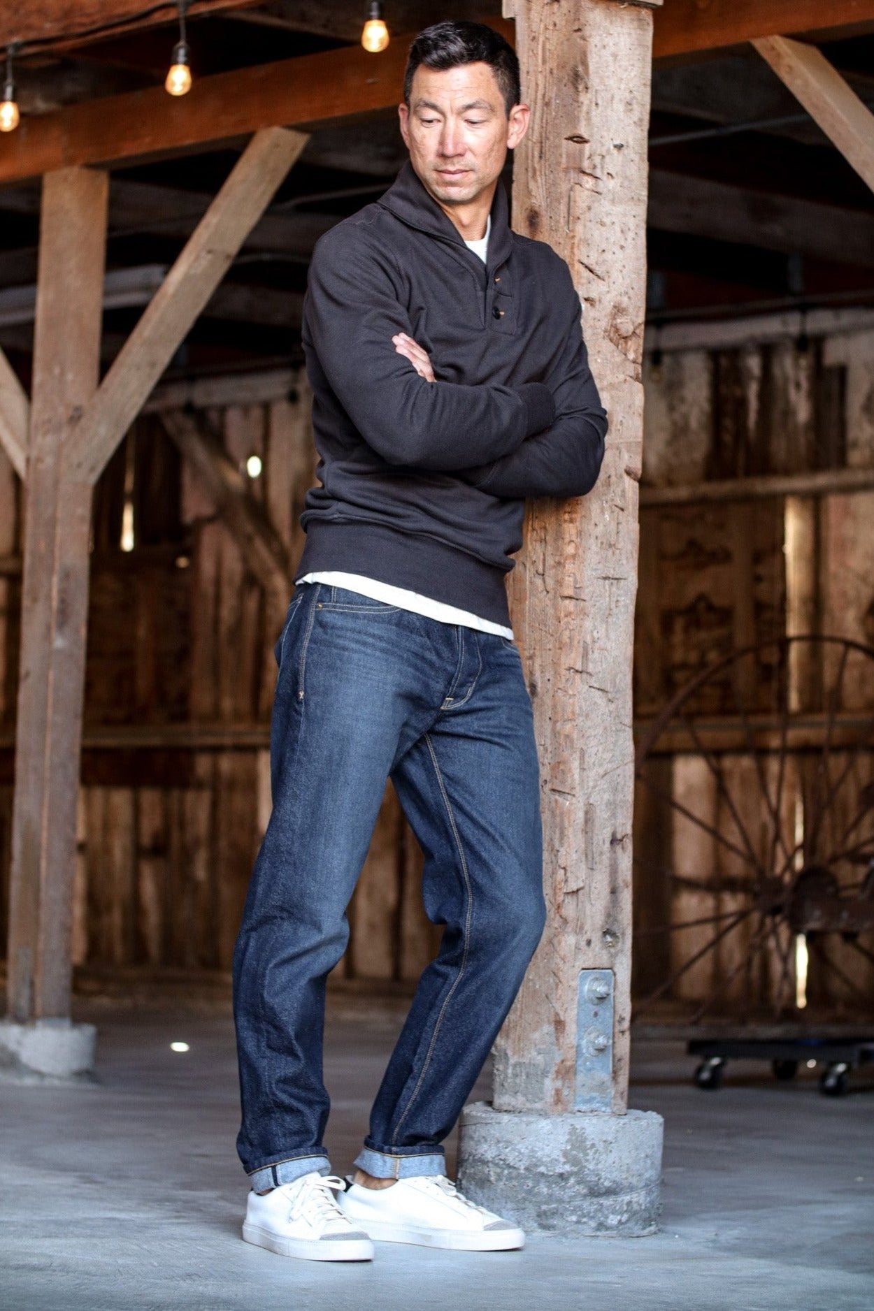 Collared cardigan men's in black with a sleek fit, styled with cuffed jeans and white sneakers in a rustic setting.