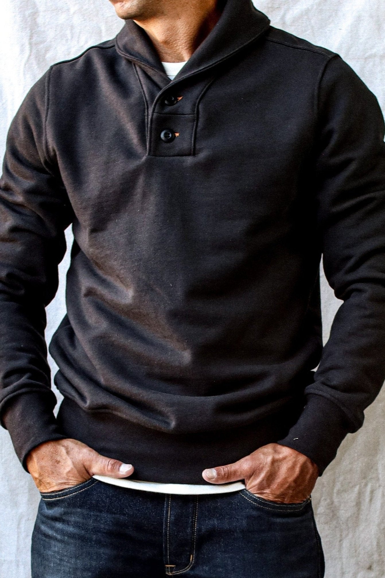 Men's cotton shawl collar cardigan in black with button detailing, paired casually with dark denim and a white undershirt.