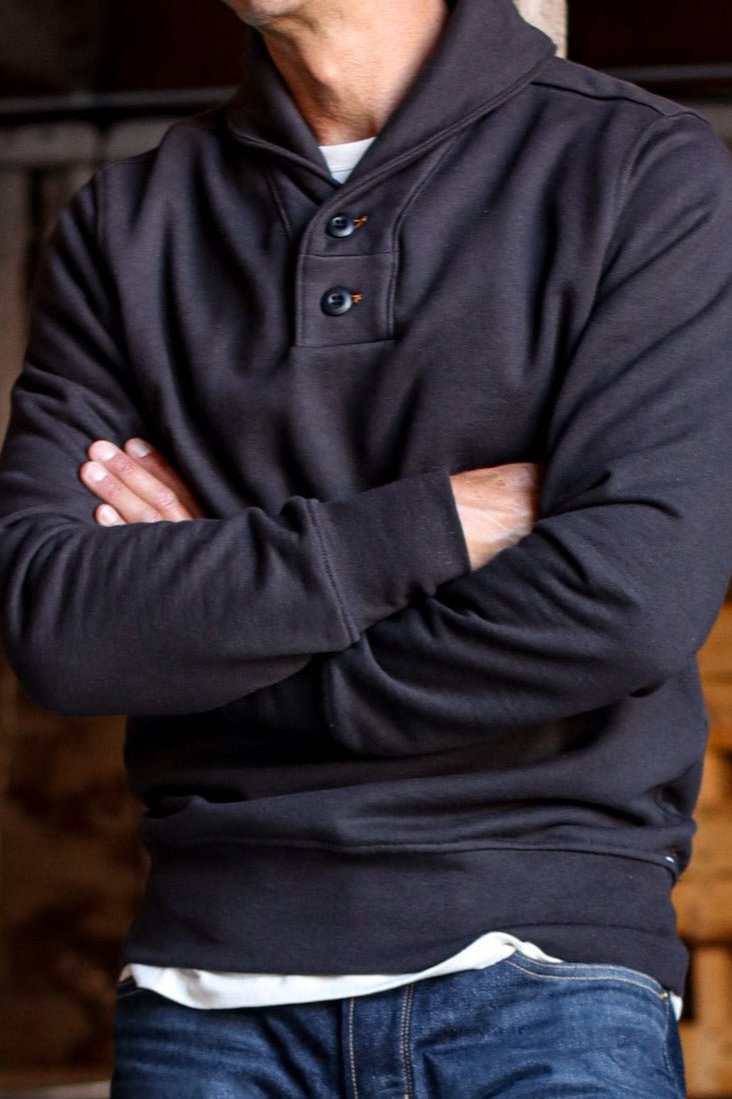 Men shawl cardigan in black with a buttoned neckline, styled casually over a white undershirt and jeans.