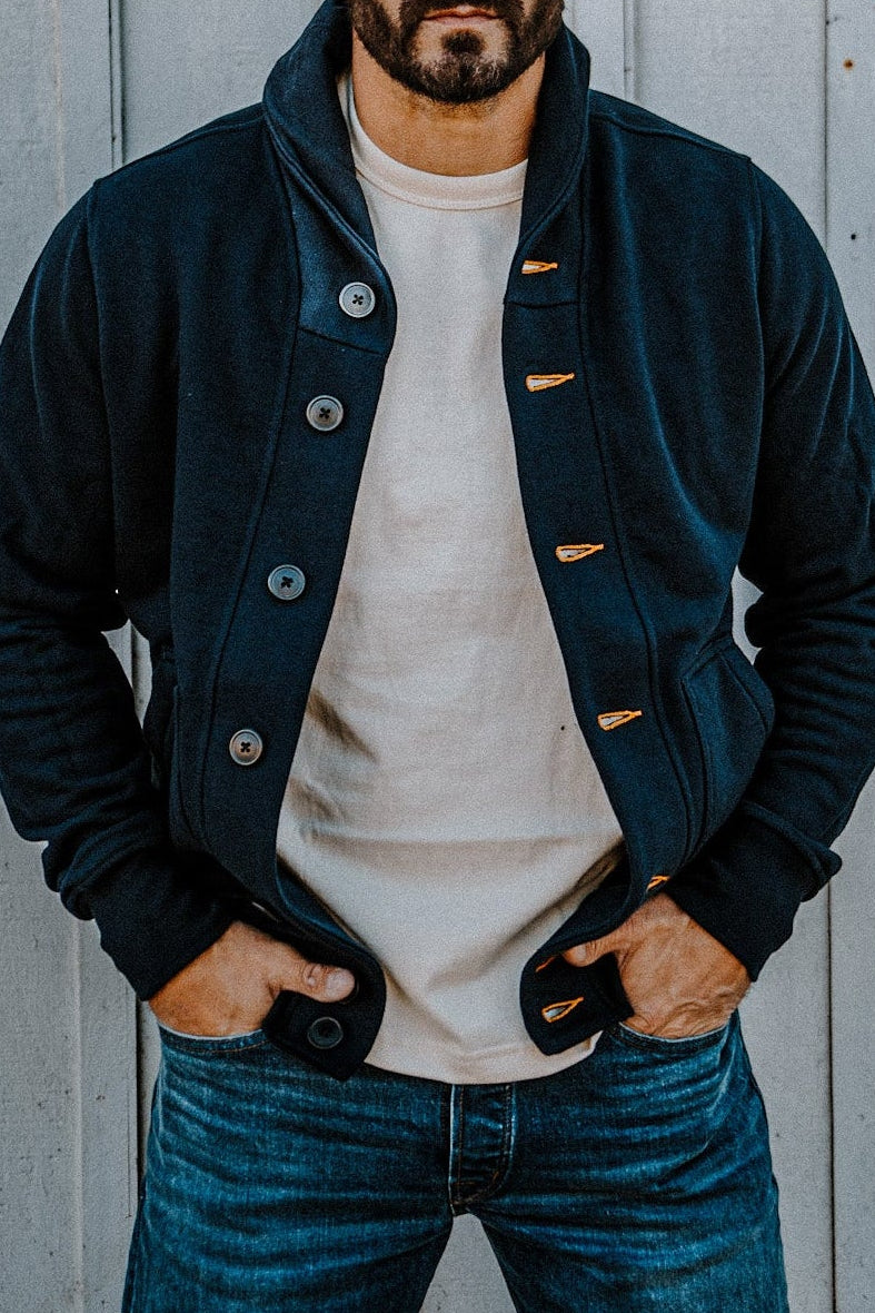 Man wearing an open men's navy French terry cardigan over a cream tee, hands in pockets