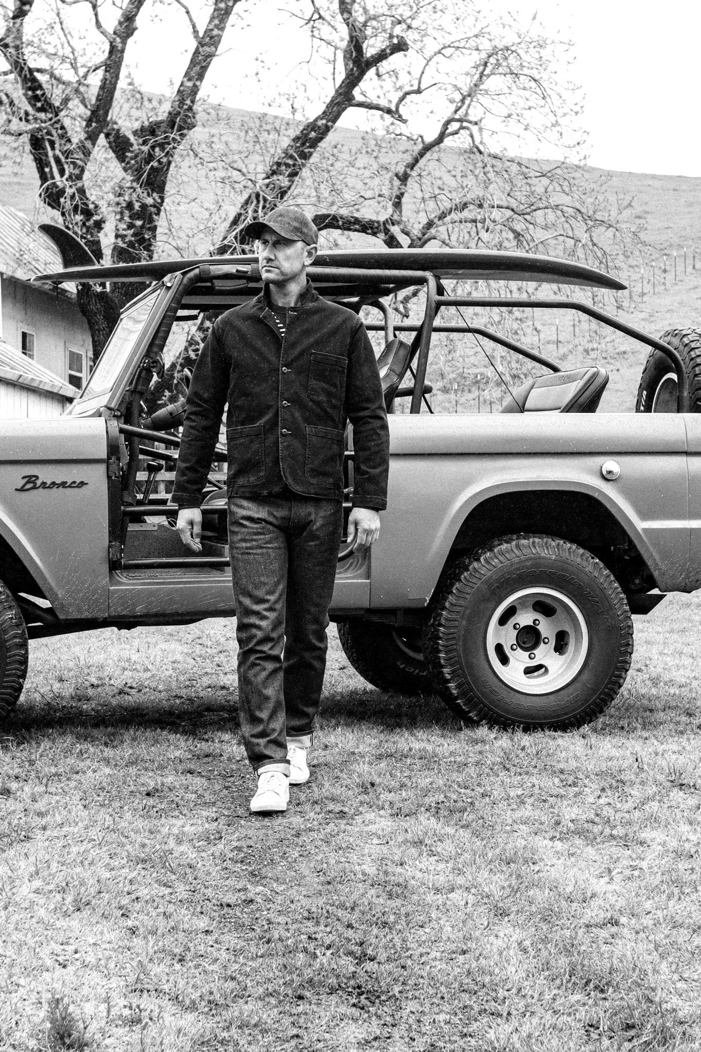 Best luxury jeans for men captured in a timeless black-and-white setting, featuring a slim fit and refined craftsmanship, paired with a structured jacket and sneakers for a sophisticated, rugged aesthetic