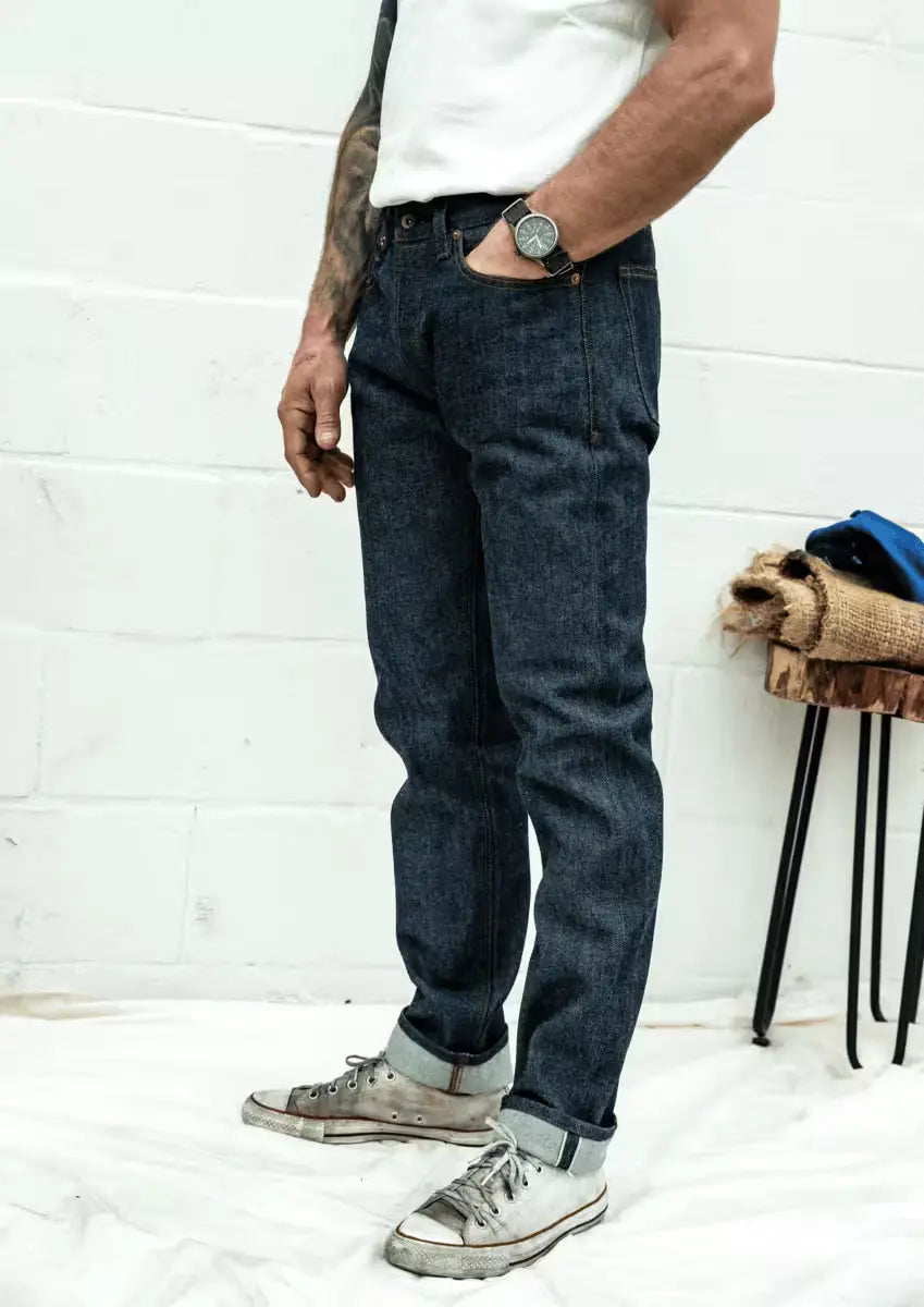 Man wearing Sam Fit Jean in Raw Selvedge color styled with rolled cuffs & casual sneakers