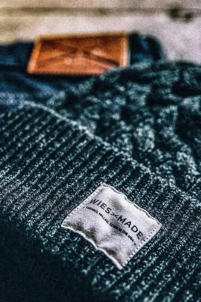 Wool beanie in navy color, crafted from cable-knit wool, featuring a branded label stitched on the folded brim