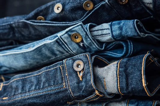 Ring-spun cotton jeans stacked in a pile, showcasing durable denim fabric and metal button details