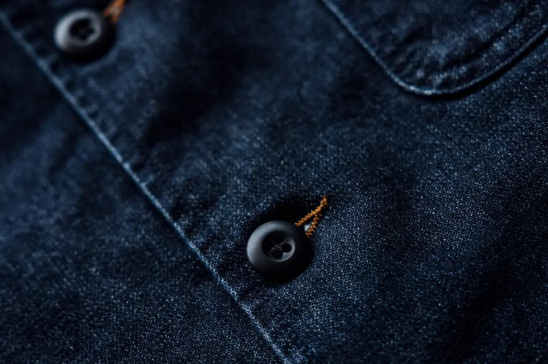 Long-lasting durable denim fabric with a close-up of a dark blue button and contrast stitching detail