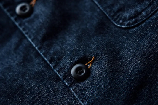 Long-lasting durable denim fabric with a close-up of a dark blue button and contrast stitching detail