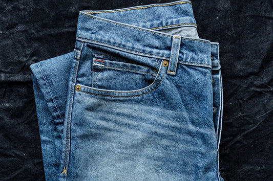 Small-batch clothing jeans folded to showcase faded denim, precise stitching, and premium fabric texture