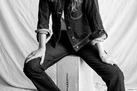 Denim jeans for women styled with a matching jacket and rolled cuffs in a studio portrait