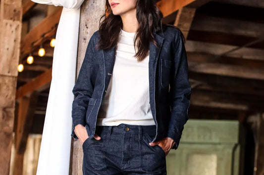 Luxury denim suit worn by a woman in a rustic barn, pairing tailored pants with a matching jacket