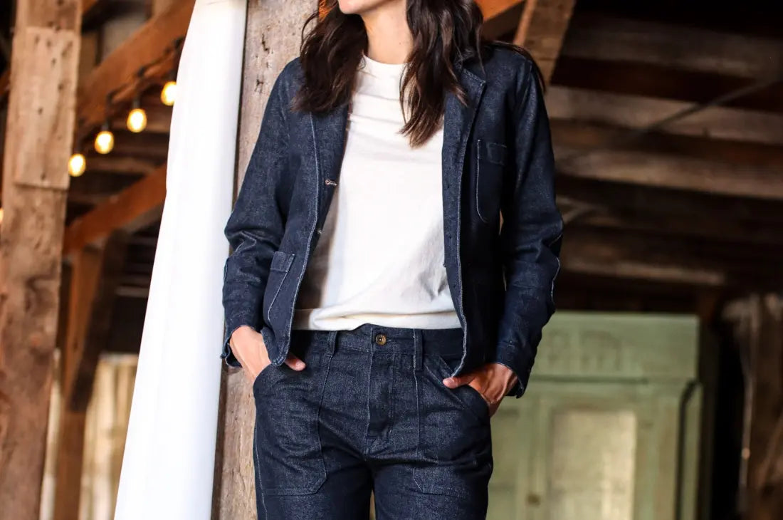 Vintage jeans for women paired with a dark denim jacket and white shirt in a rustic barn setting.