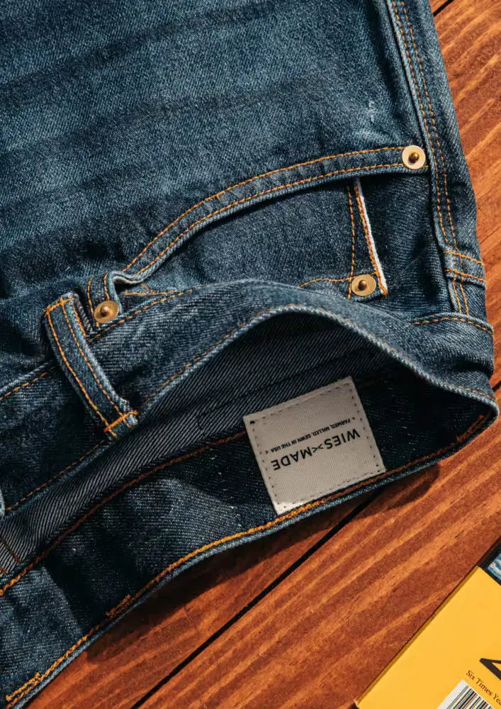 Wiesz-Made Sam Fit denim jeans in Washed Selvedge color with visible stitching and branding tag displayed on a wooden surface 