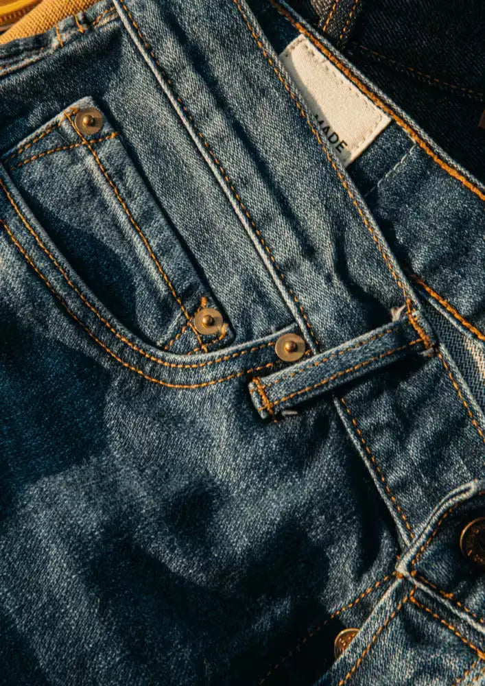 Sam Fit Jean in River Wash color featuring brass rivets, contrast stitching, & Wiesz-Made branding tag