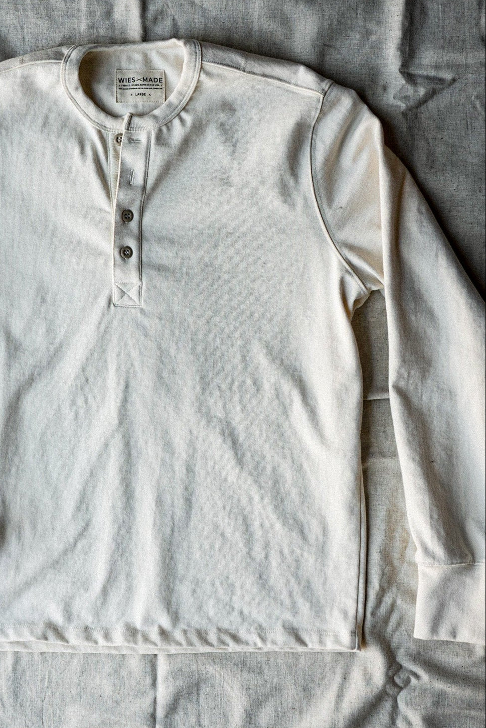 Flat lay of a men's natural cotton henley shirt with a button-front placket and long sleeves