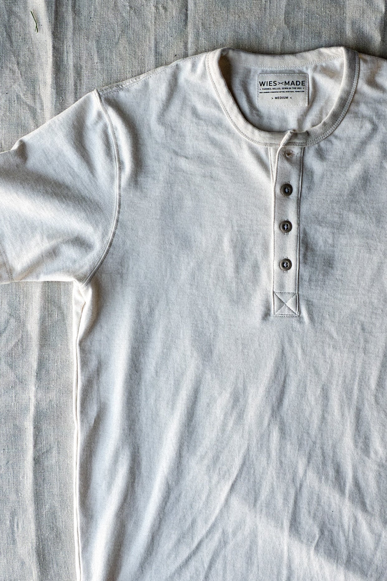 Natural cotton Bolinas Henley laid flat, showing four-button placket and WiesMade neck label.