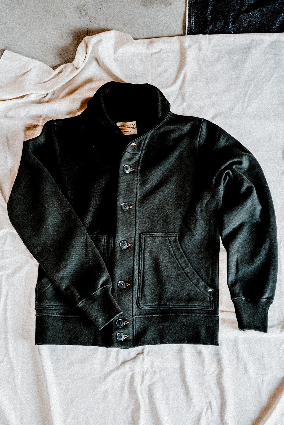 Men's basalt French terry cardigan laid flat, showing the shawl collar, button-front closure, and patch pockets