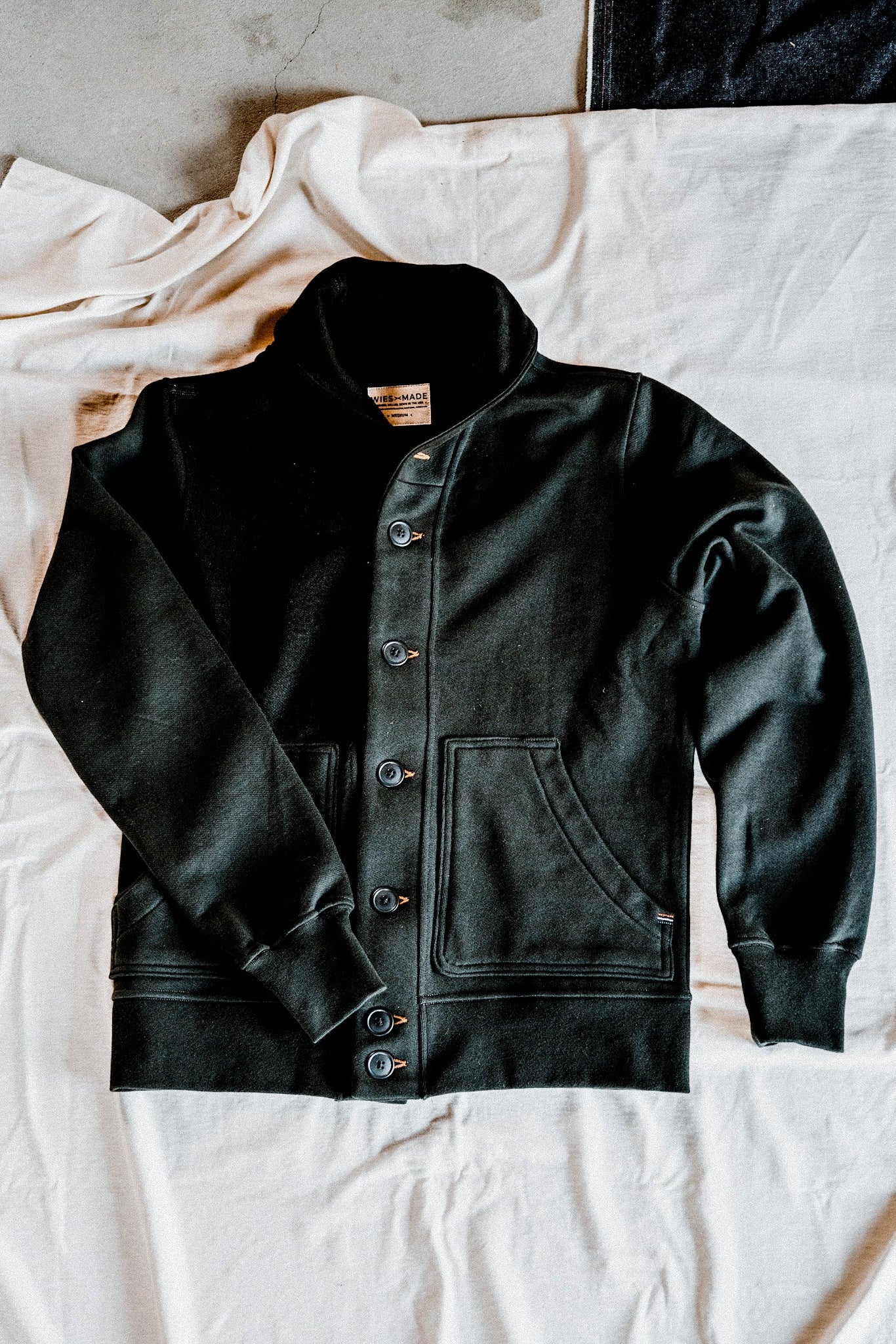 Men's basalt French terry cardigan laid flat, showing the shawl collar, button-front closure, and patch pockets