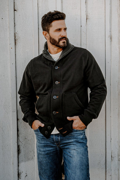 Man wearing a men's basalt French terry cardigan with hands in pockets, looking to the side