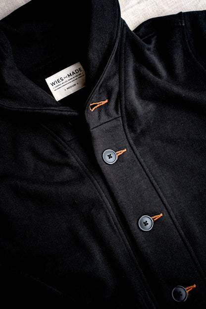 Close-up of the Bodega shawl cardigan in black French terry with tobacco-thread keyhole buttonholes and WiesMade label.