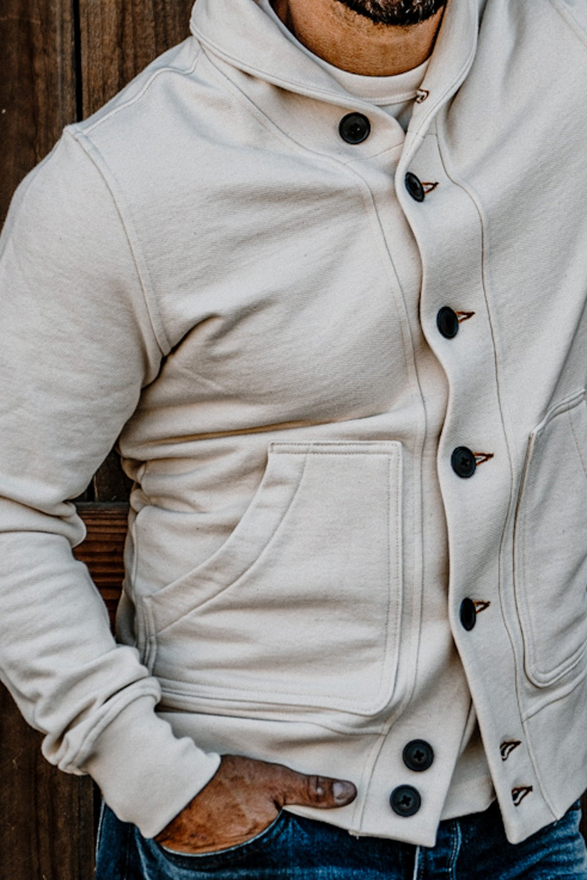 Close-up of a men's heavyweight fleece cardigan showing horn-style buttons, contrast stitching, and a front patch pocket.