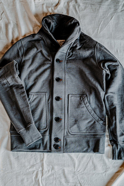 Men's pebble French terry cardigan laid flat, showing the shawl collar, button-front closure, and patch pockets