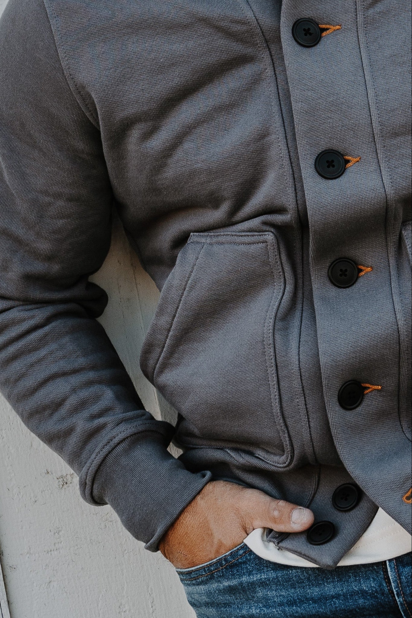 Close-up detail of a men's pebble French terry cardigan showing the button-front closure and patch pocket