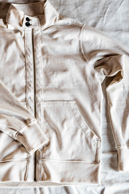 Flat lay of a men's cream zip-up moto jacket showing the snap collar and front pocket