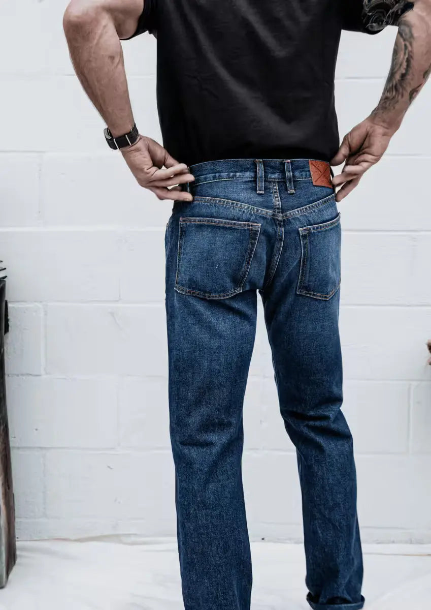 Man wearing a Sam Fit jeans in Washed Selvedge color featuring a classic back pocket design and leather brand patch