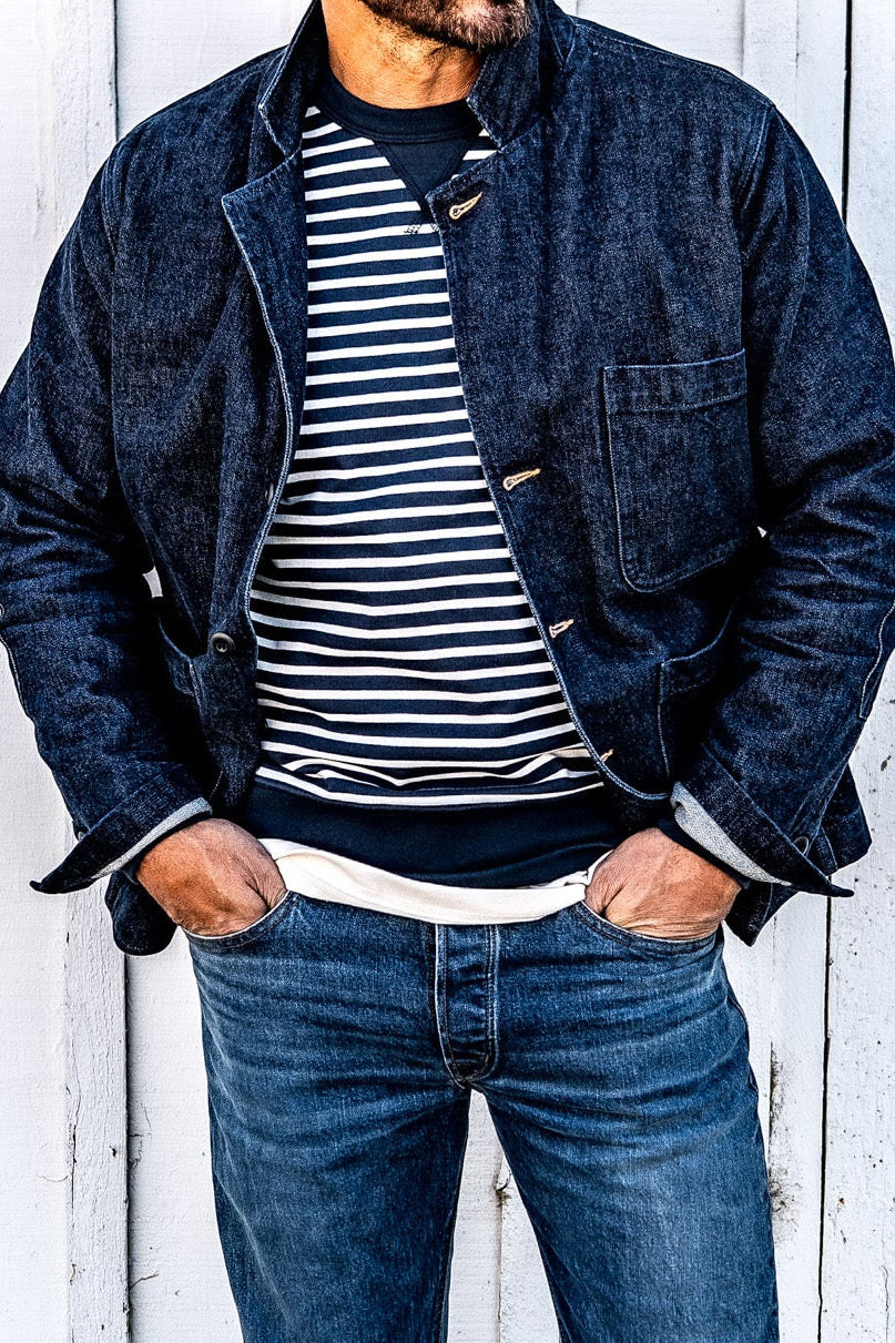 Close-up of a man's chest and torso in a men's ocean denim chore blazer worn open over a striped shirt