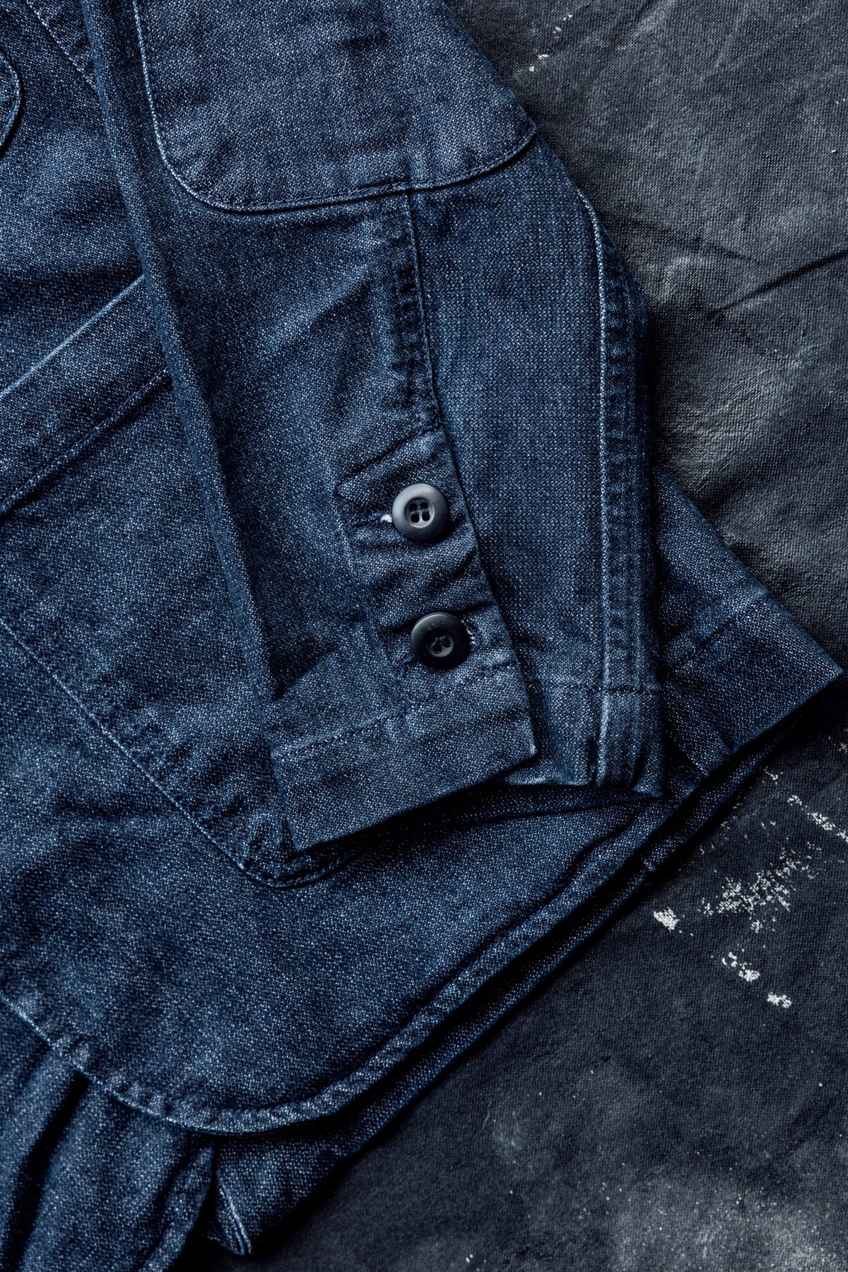 Close-up of the button cuff and sleeve hem detail on a men's ocean denim chore blazer