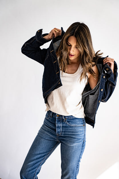 American made denim jacket layered over a white tank top and paired with high-waisted jeans, styled casually.