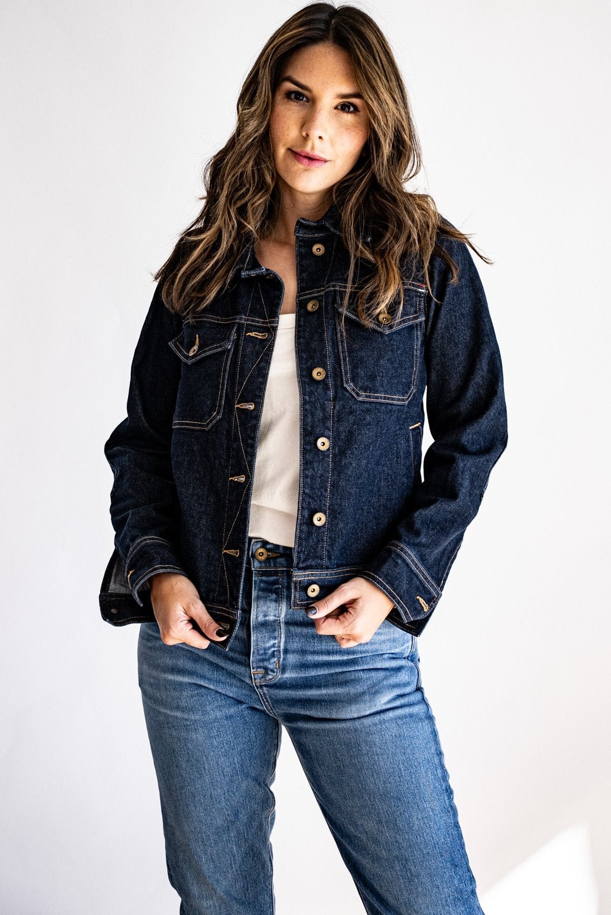 dark made in USA denim jacket styled with a white tank top and light-wash jeans, modeled against a bright background.
